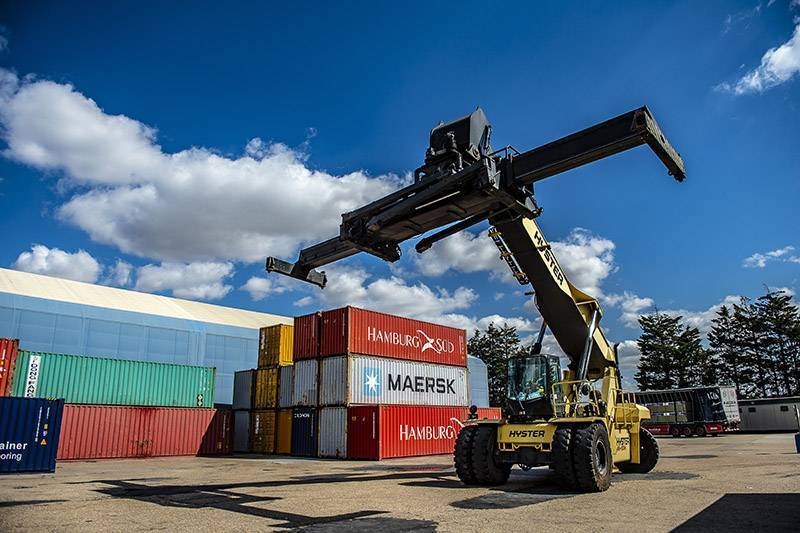 A reachstacker picking up colourful containers on a sunny day