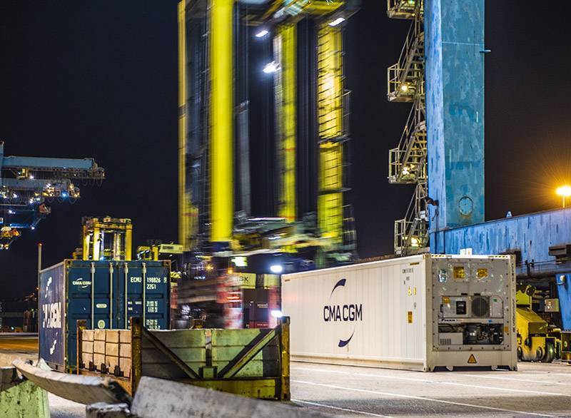 Straddle carriers moving boxes at night at London Container Terminal